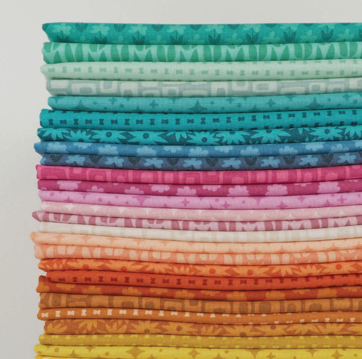 Stack of colorful fabrics in shades of teal, blue, pink, orange, and yellow with subtle patterns from Elizabeth Hartman's Scenery Fabric Collection, suitable for modern needlework projects.