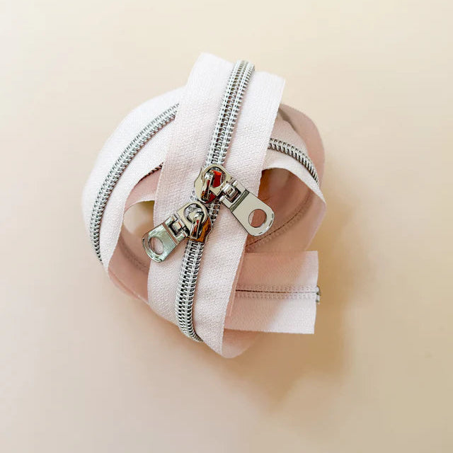 Close-up of a pink fabric pouch with a zipper on a beige background