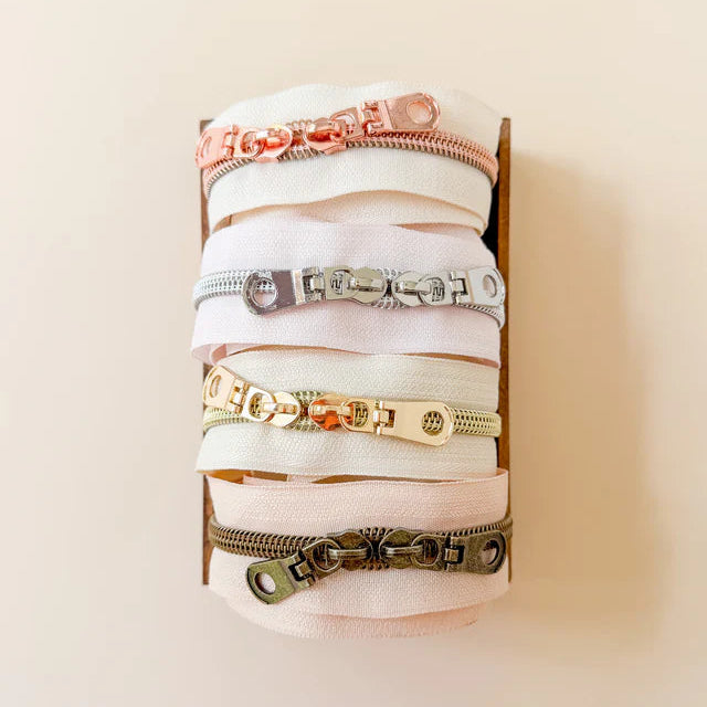 Collection of zippers on a white stand against a beige background