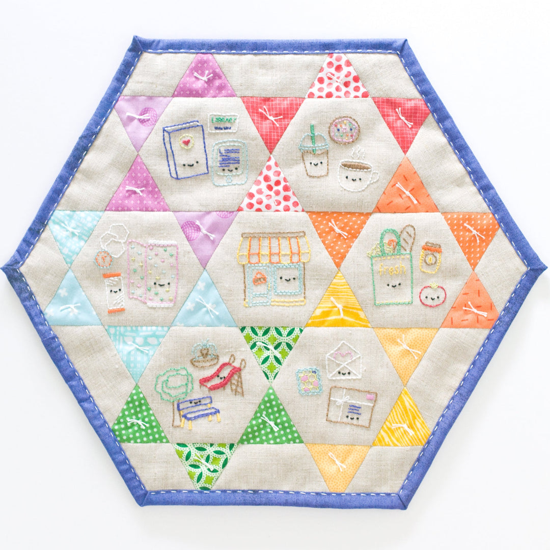 Hexagonal quilted placemat with colorful geometric patterns on a white background