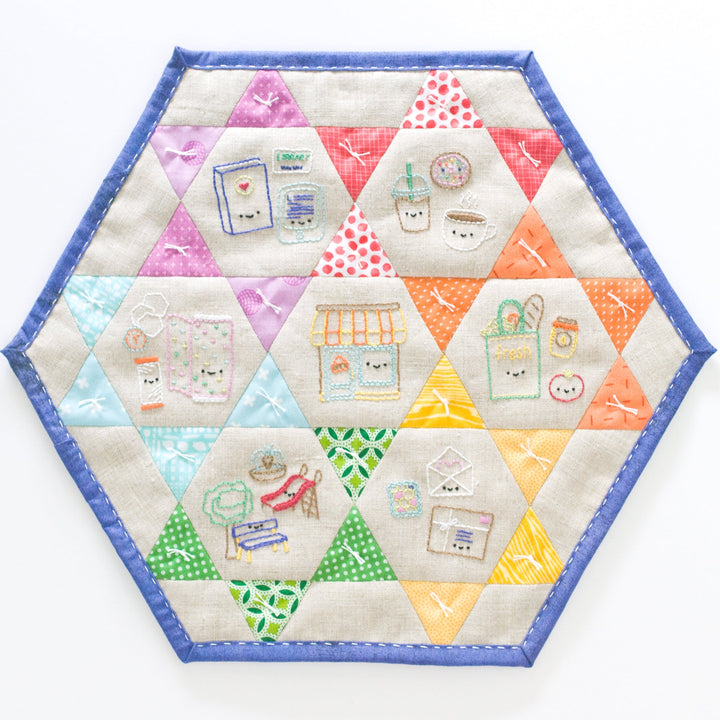 Hexagonal quilted placemat with colorful geometric patterns on a white background