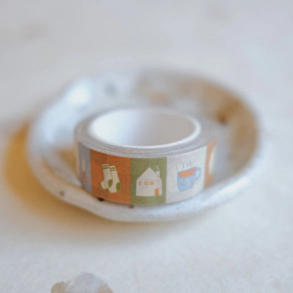 At Home Washi Tape featuring cozy illustrations of socks, a house, and a cup resting on a small ceramic dish, ideal for journaling and crafting projects.