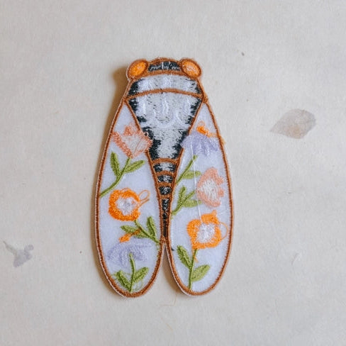 Cicadas Embroidered Iron-on Patch featuring detailed stitching with floral patterns in orange, green, and lavender on a white background, ideal for modern needlework projects.