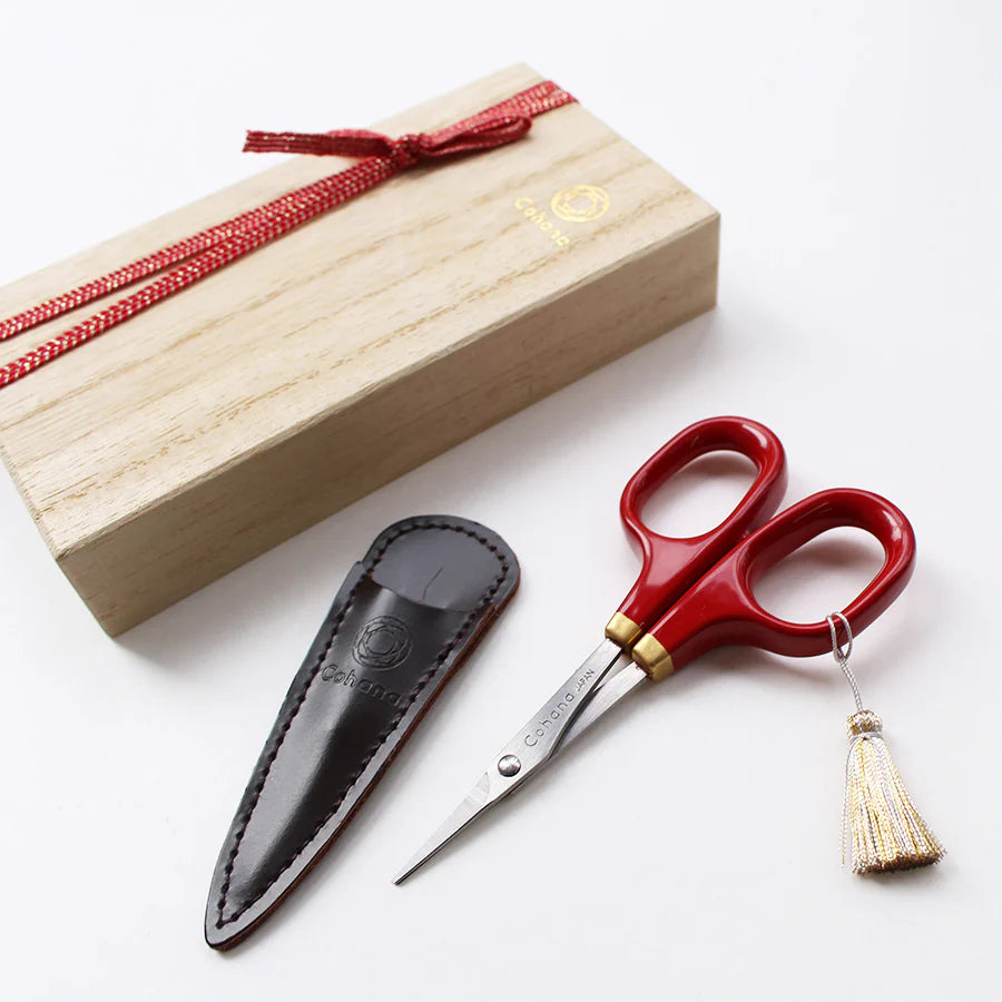Japanese Artisan Lacquered Handle Embroidery Scissors with deep red lacquered handles, brass accents, a decorative tassel, and a black leather sheath, presented alongside a wooden gift box.