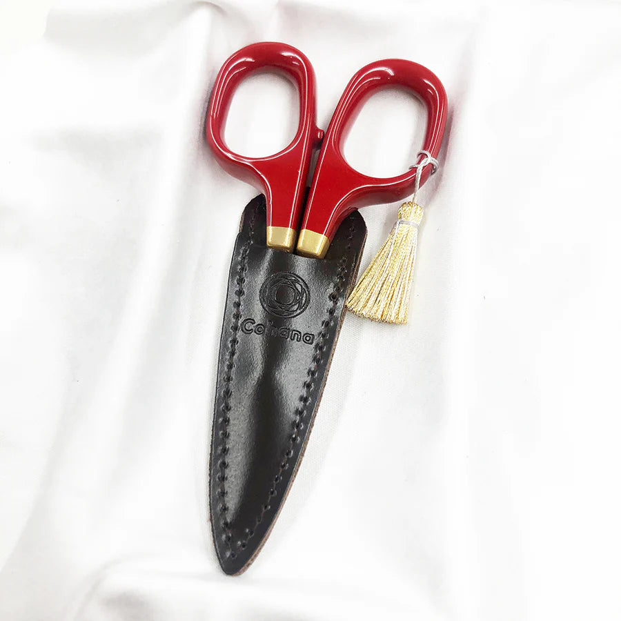 Japanese Artisan Lacquered Handle Embroidery Scissors with glossy red handles and gold accents, resting in a black leather sheath, ideal for precise needlework and craft projects.