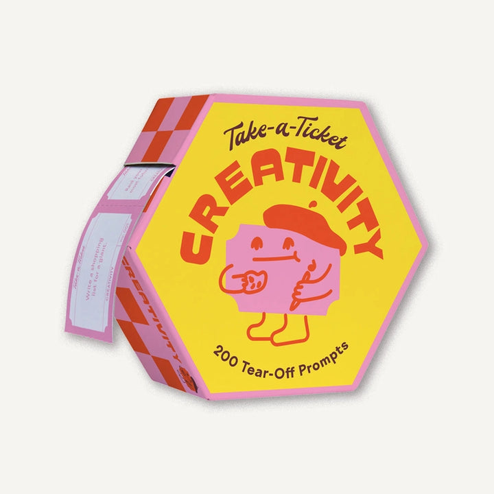 Hexagonal yellow and pink box labeled Take-A-Ticket: Creativity Prompts featuring a cartoon character wearing a beret, containing 200 tear-off creativity prompt tickets.