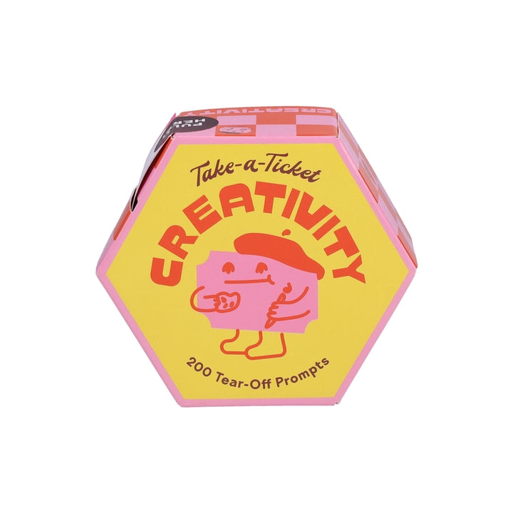 Hexagonal yellow and pink box featuring a smiling character holding a coffee cup, labeled Take-A-Ticket: Creativity Prompts with 200 tear-off prompts for creative inspiration.