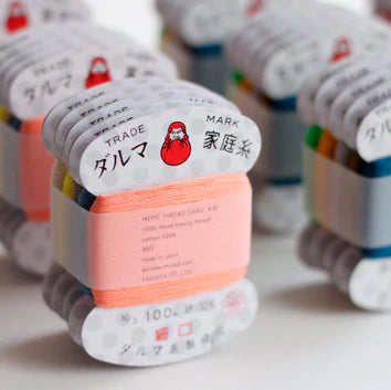 Close-up of pastel pink embroidery thread in Daruma Home Thread #30 Carded Collections with Japanese craft design, surrounded by colorful varieties for modern needlework projects.