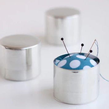 Artisan Made Japanese Pin Cushion featuring a polished metal base with a blue fabric top accented by large white polka dots, holding sewing needles and thread for modern needlework.