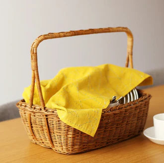 Yellow fabric with subtle stitched patterns displayed in a wicker basket, showcasing the Half-Yard 5mm Straight Line Grid Sashiko Sampler for modern needlework and Sashiko supplies.