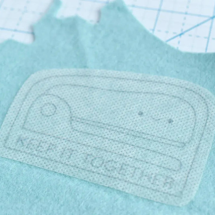 Embroidered patch on a light blue fabric with a grid background