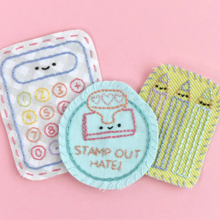 Three embroidered patches on a pink background, including a calculator, a stamp, and birthday candles.