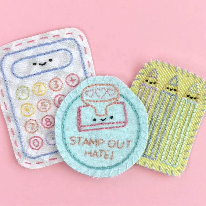 Three embroidered patches on a pink background, including a calculator, a stamp, and birthday candles.