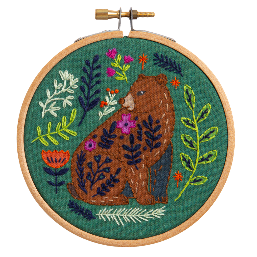 Embroidery hoop with a bear and floral design on a green background