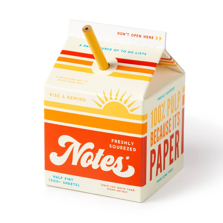 Brass Monkey Freshly Squeezed Note Pad designed like a vintage juice carton with bright orange and yellow stripes, featuring a pencil inserted at the top.
