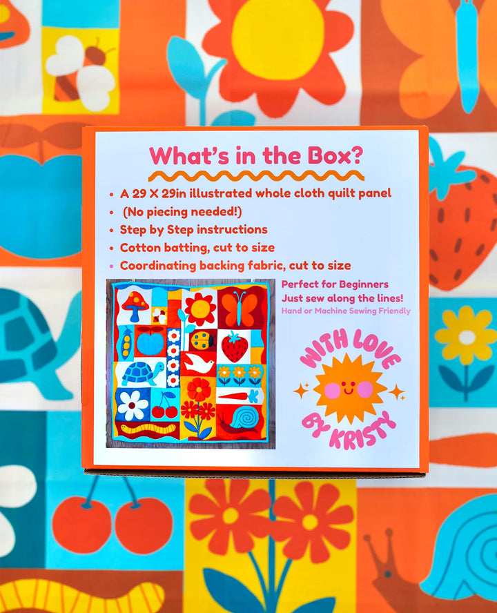 Brightly colored informational card for the Garden Charms Whole Cloth Quilt Kit showing quilt panel design with flowers, fruits, and animals on a vibrant fabric background.