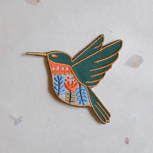 Hummingbird Embroidered Iron-on Patch featuring detailed stitching in green, orange, and blue with floral embroidery, perfect for enhancing fabric in modern needlework projects.