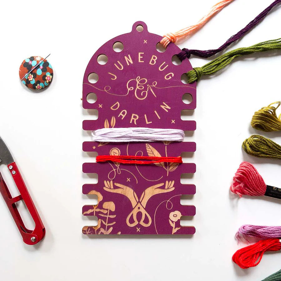 Magenta wooden thread organizer with both slots for winding thread and holes for looping