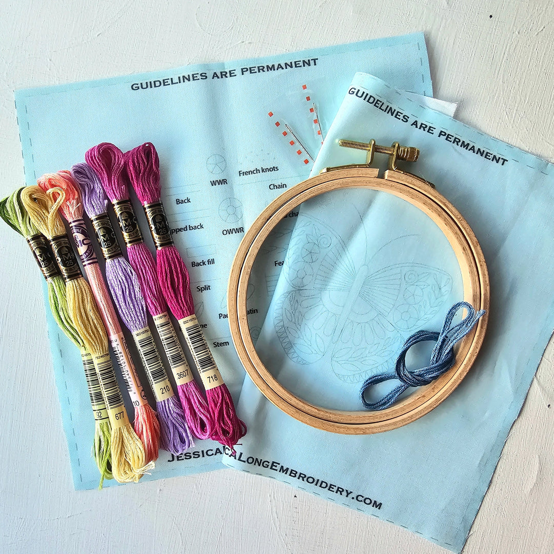 Beginner Butterfly Sampler Hand Embroidery Kit featuring colorful embroidery floss, a wooden hoop, printed fabric with butterfly design, and stitching guidelines for hand embroidery.