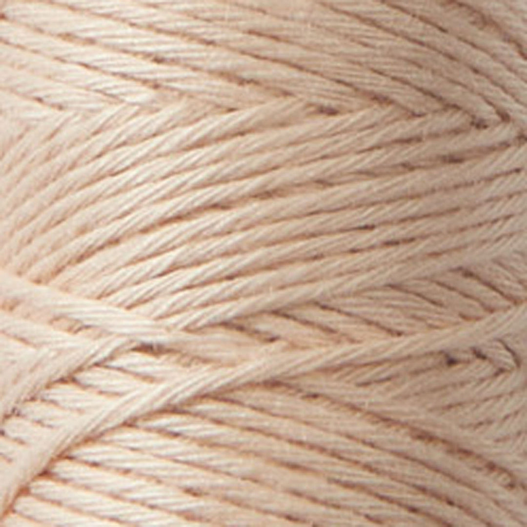Close-up of tightly wound soft peach-colored Cosmo Hidamari Sashiko Thread - Peach Fuzz (#33) ideal for Japanese craft supplies and modern needlework projects.