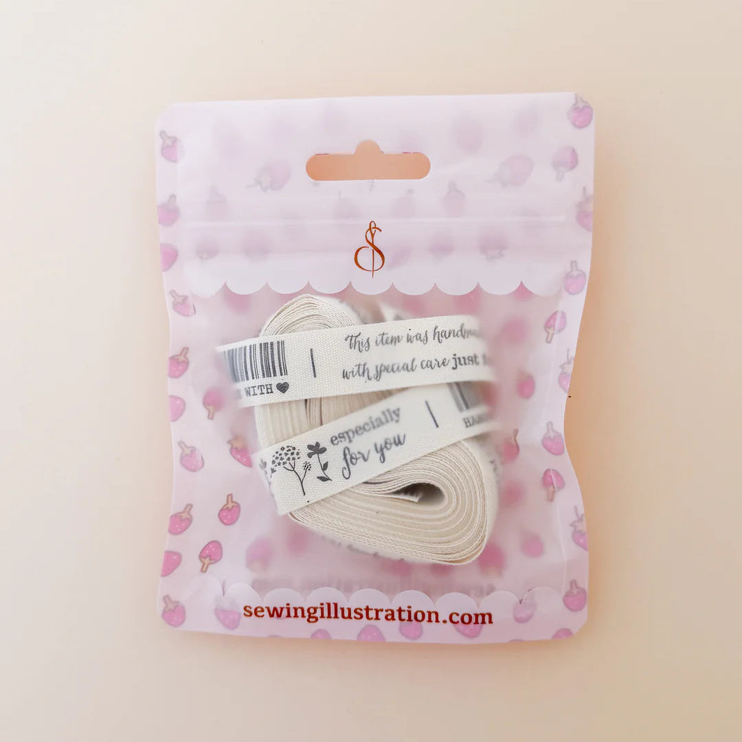 Packaged sewing thread with a pink patterned package on a beige background
