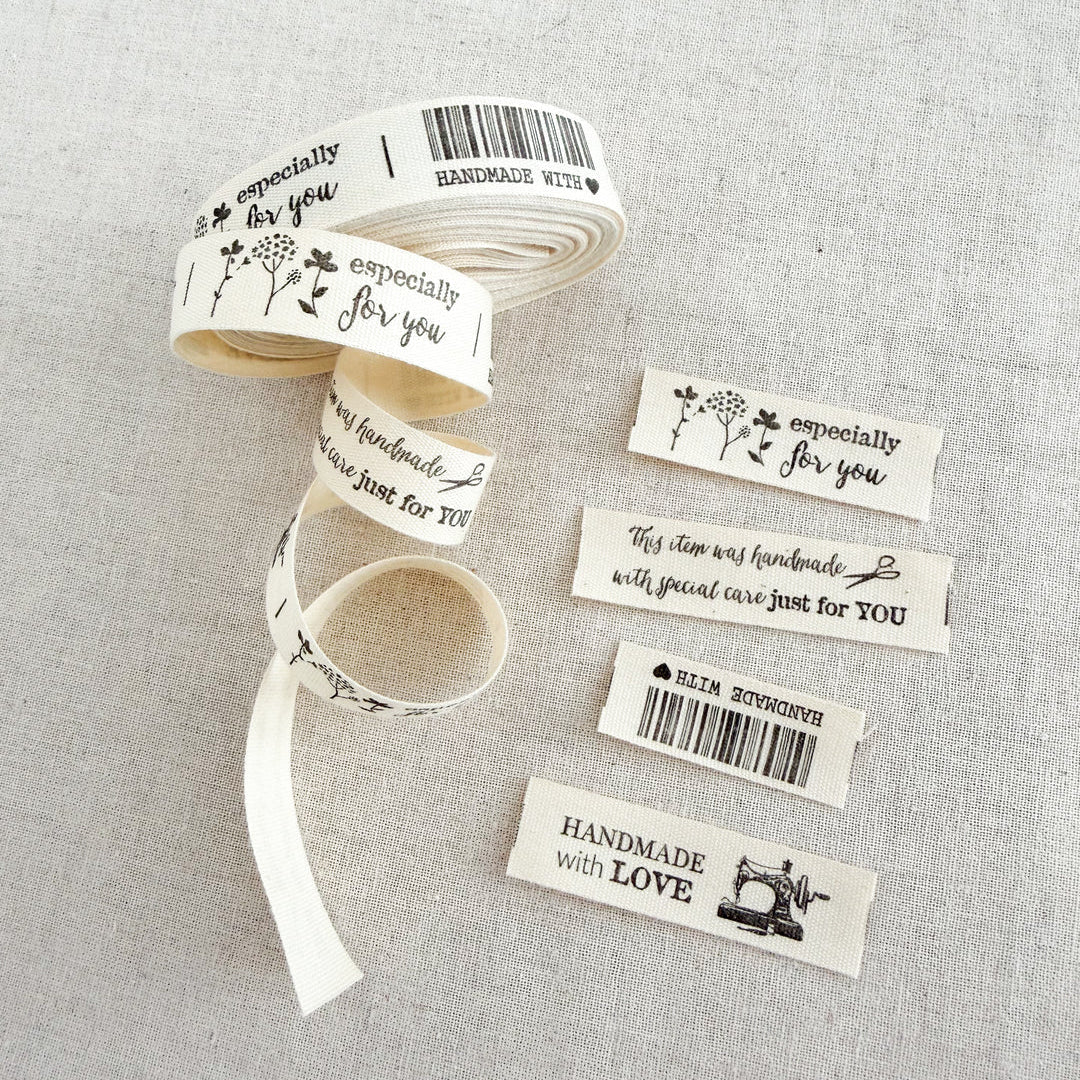 Roll of ribbon with printed labels on a gray fabric background