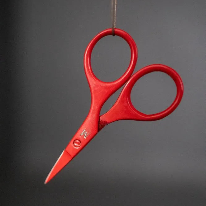 Red scissors hanging from a string against a dark background