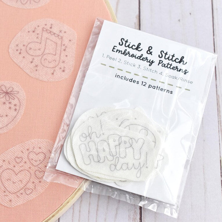 Packaging of stick and stitch embroidery patterns on a pink background with sample designs.