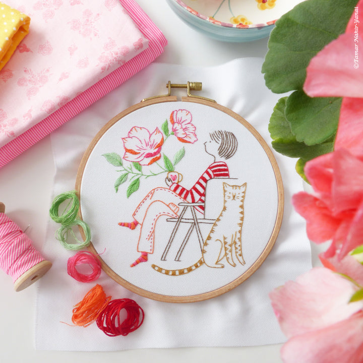 Me & My Tiger Embroidery Kit showing a hand-stitched design of a seated person with flowers and a striped cat, surrounded by colorful embroidery threads and soft fabrics.