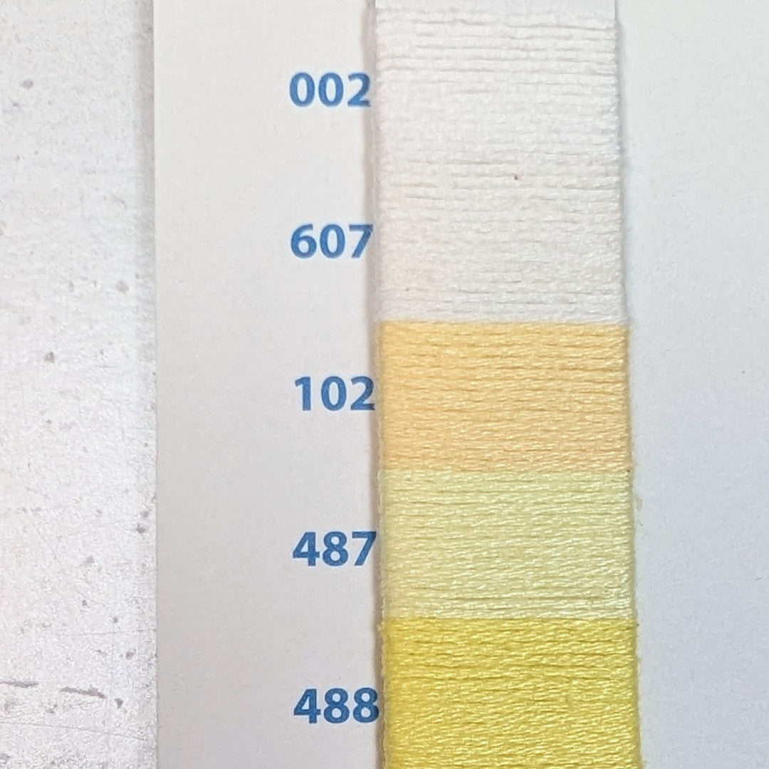 Close-up of a color chart showing a gradient of light yellow and white shades of Hilo Vela El Globo Embroidery Thread (8m Skeins) - Light Yellows with labeled thread numbers.