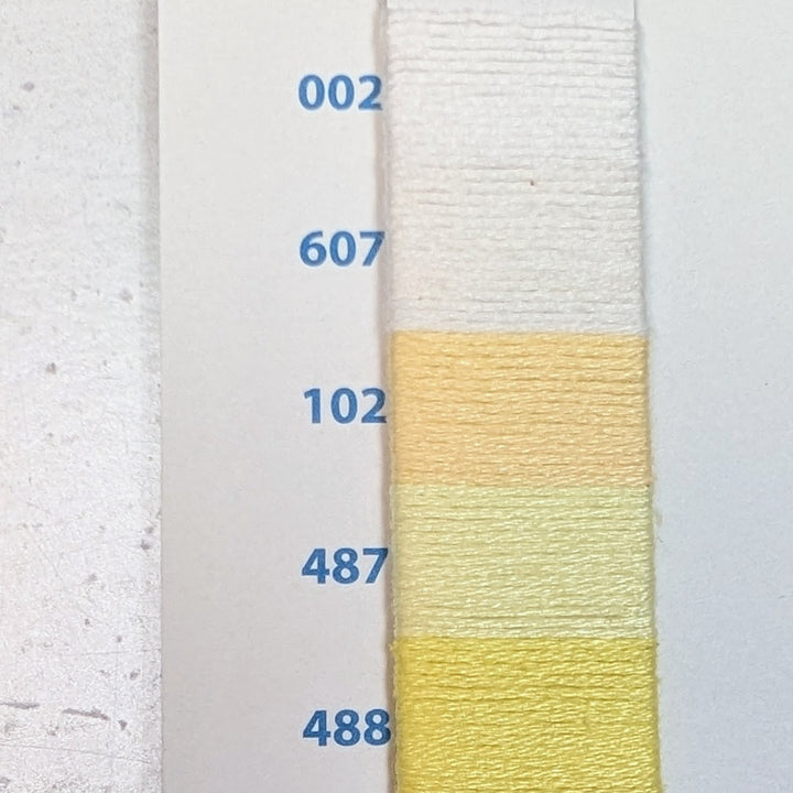 Close-up of a color chart showing a gradient of light yellow and white shades of Hilo Vela El Globo Embroidery Thread (8m Skeins) - Light Yellows with labeled thread numbers.
