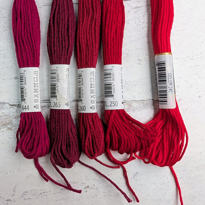 Hilo Vela El Globo Embroidery Thread (8m Skeins) - Reds in various shades, displayed on a light textured surface, ideal for embroidery, cross stitch, and modern needlework.