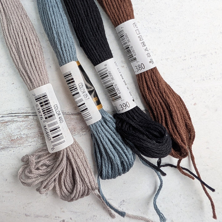 Four skeins of Hilo Vela El Globo Embroidery Thread (8m Skeins) - Neutrals in soft taupe, muted blue, deep black, and rich brown, perfect for modern needlework and Japanese craft supplies.