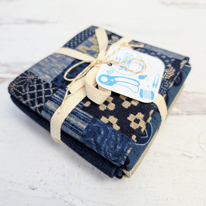 Homespun Rustic Weave Fat Quarter Bundle neatly folded and tied with cream-colored ribbon, featuring navy and beige woven patterns, perfect for modern needlework and sewing projects.