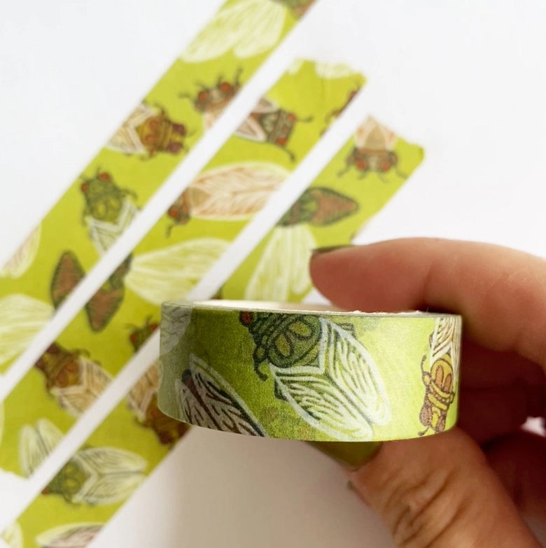 Hand holding Cicadas Washi Tape with green background and detailed cicada illustrations, shown next to strips of the tape for crafting or Japanese stationery use.