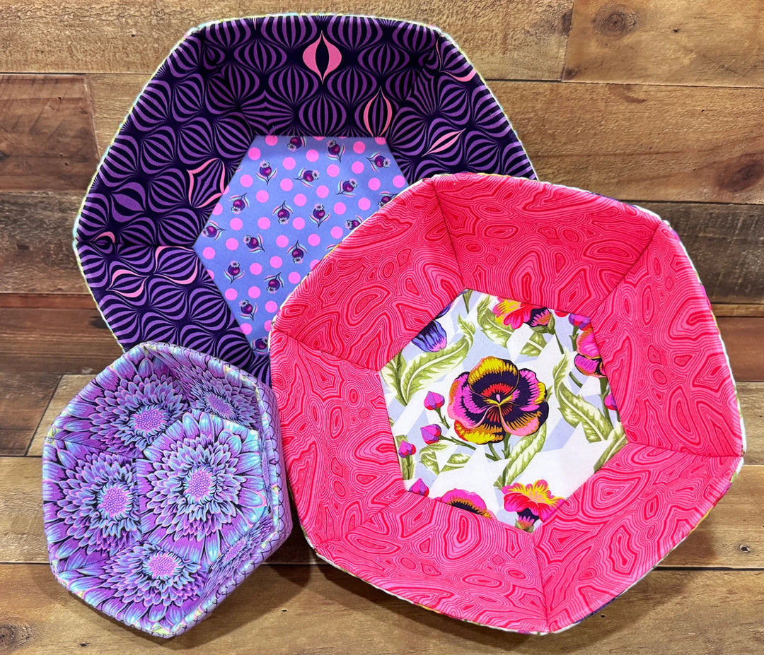 Three fabric bowls featuring colorful, patterned hexagons made with the English Paper Piecing Bowls Pattern - The Prosperity Bowl, showcasing modern needlework crafts.