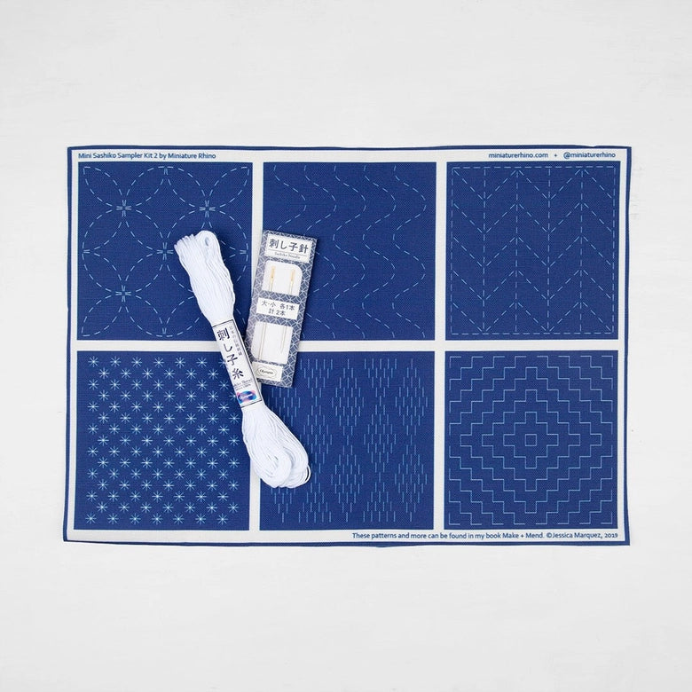 Sashiko Mini Sampler Kit (No. 2) featuring blue fabric with traditional white Sashiko embroidery patterns, including embroidery thread and needles for Japanese craft supplies.
