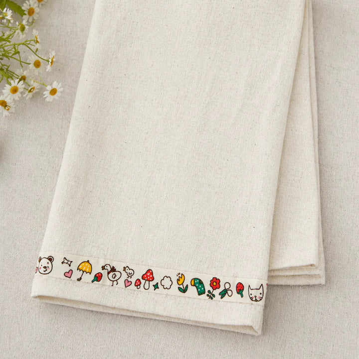 Folded white towel with embroidered designs on a light background