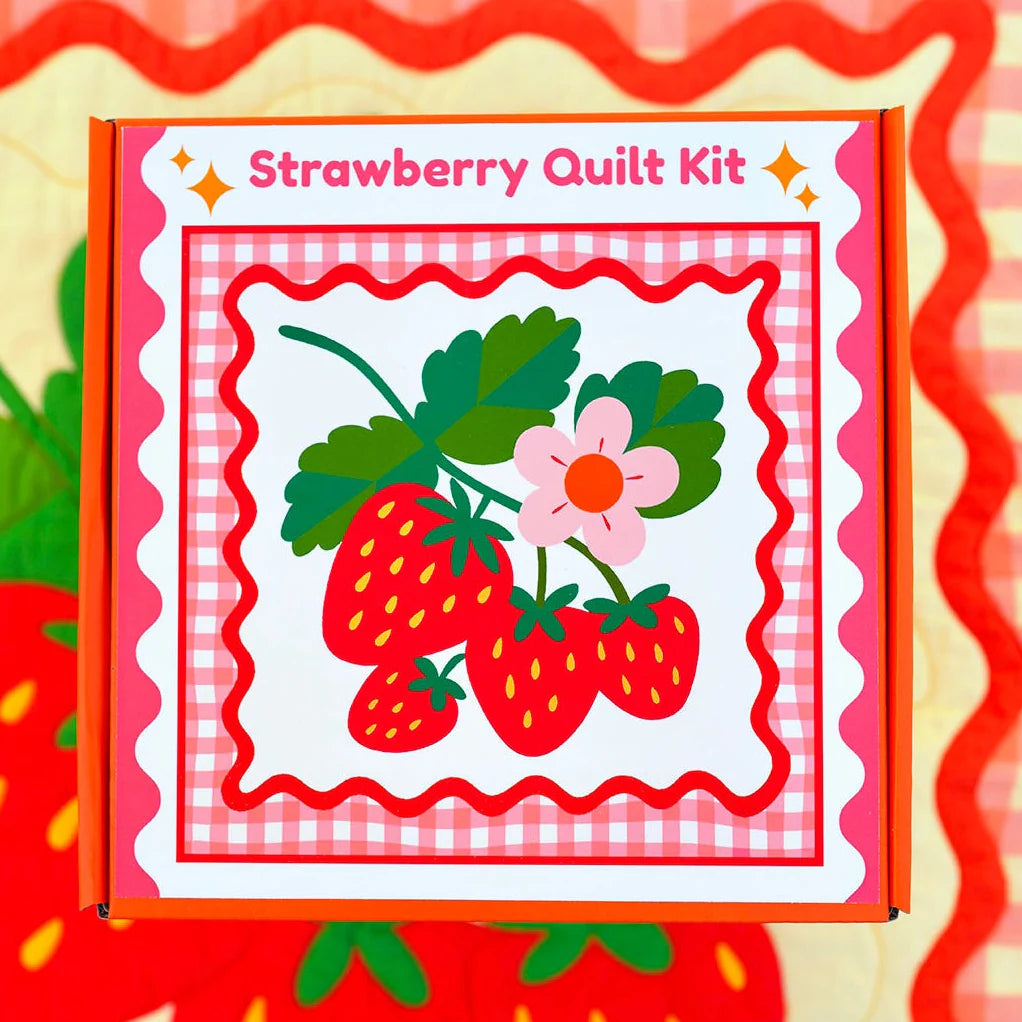 Strawberry Whole Cloth Quilt Kit featuring a vibrant design of red strawberries, green leaves, and a pink flower on a pink gingham background with red scalloped borders.