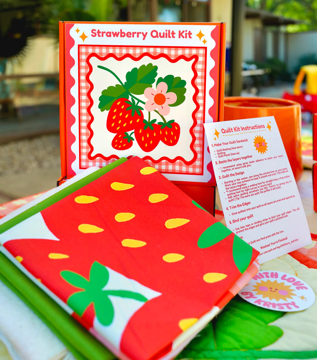 Strawberry Whole Cloth Quilt Kit featuring bright red fabric with yellow seed patterns and green leaves, styled with clear step-by-step quilt kit instructions for modern needlework craft enthusiasts.