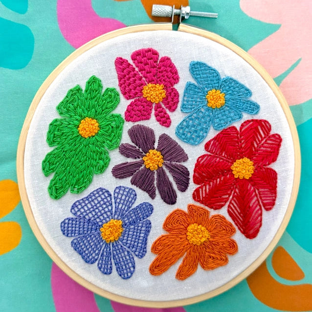 Embroidered hoop with colorful flowers on a multicolored background