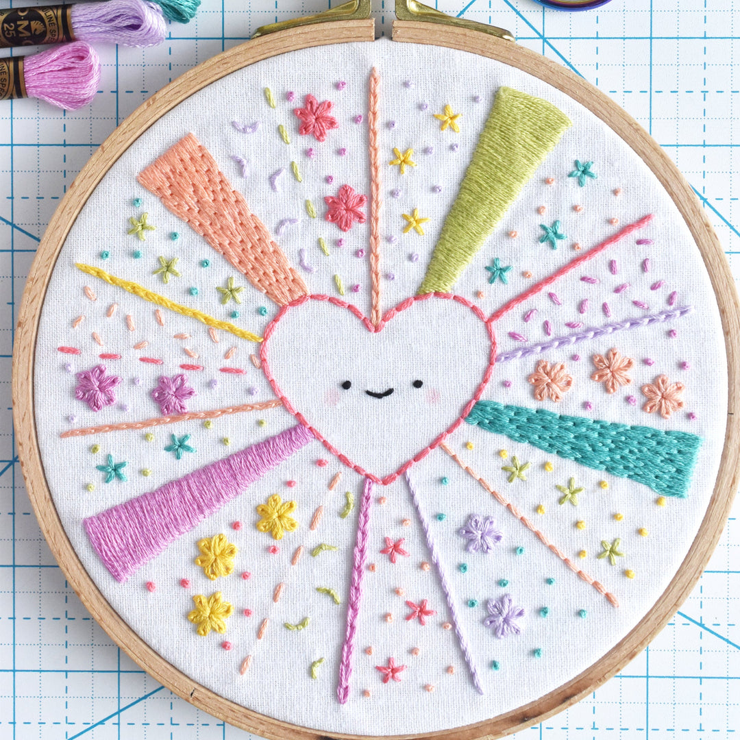 Embroidery hoop with a colorful heart design on a grid background