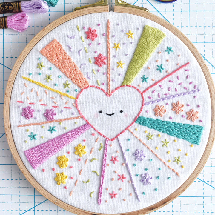 Embroidery hoop with a colorful heart design on a grid background