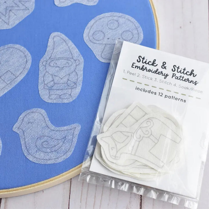 Embroidery patterns with a blue hoop and packaging on a wooden surface