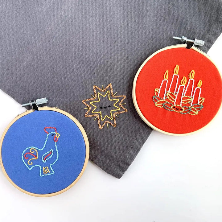 Three embroidery hoops with different designs on a gray fabric background