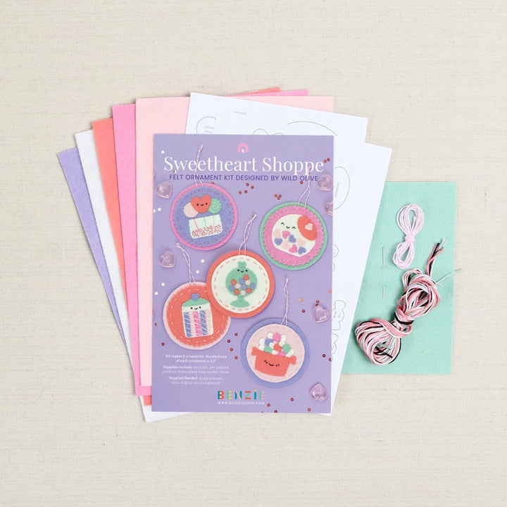 Sweetheart Shoppe Ornament Kit featuring colorful felt pieces, embroidery floss, and pattern sheets for creating cute handmade ornament decorations with modern needlework flair.