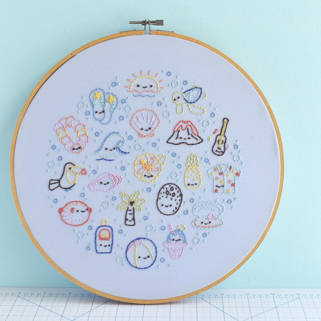 Embroidery hoop with colorful stitched designs on a light blue background