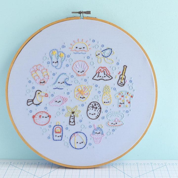 Embroidery hoop with colorful stitched designs on a light blue background