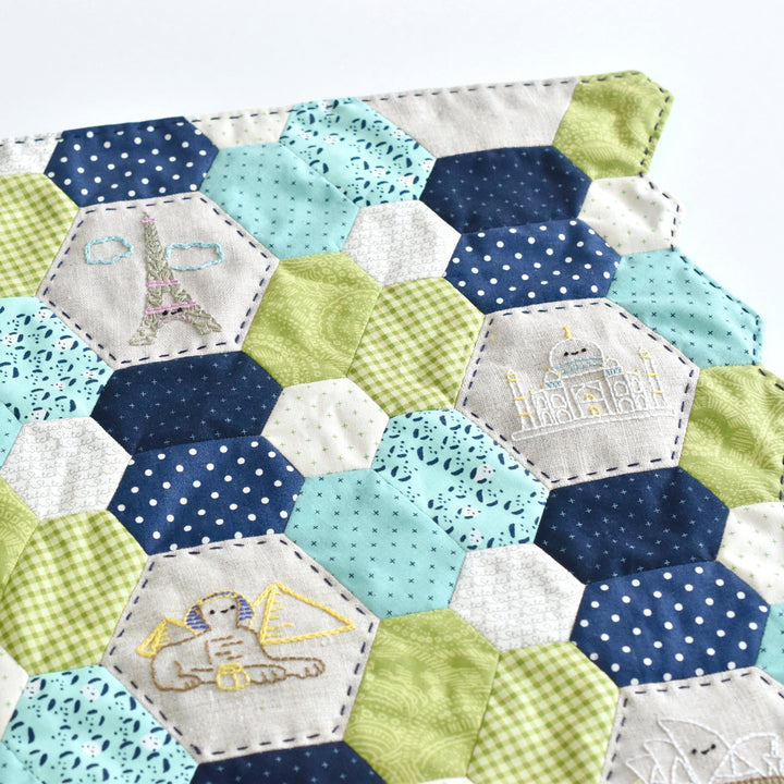 Hexagonal patchwork quilt with embroidered designs on a white background