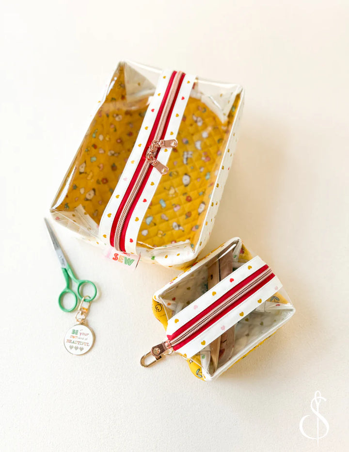 Two clear plastic bags with red and white striped handles on a white background, accompanied by a pair of green scissors.